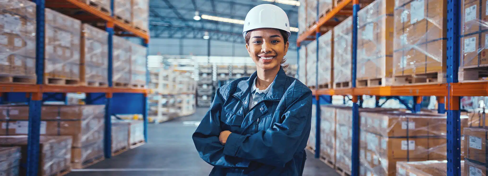 Portrait of young adult Asian tanned skin woman warehouse worker smiling, arms crossed with confidence.