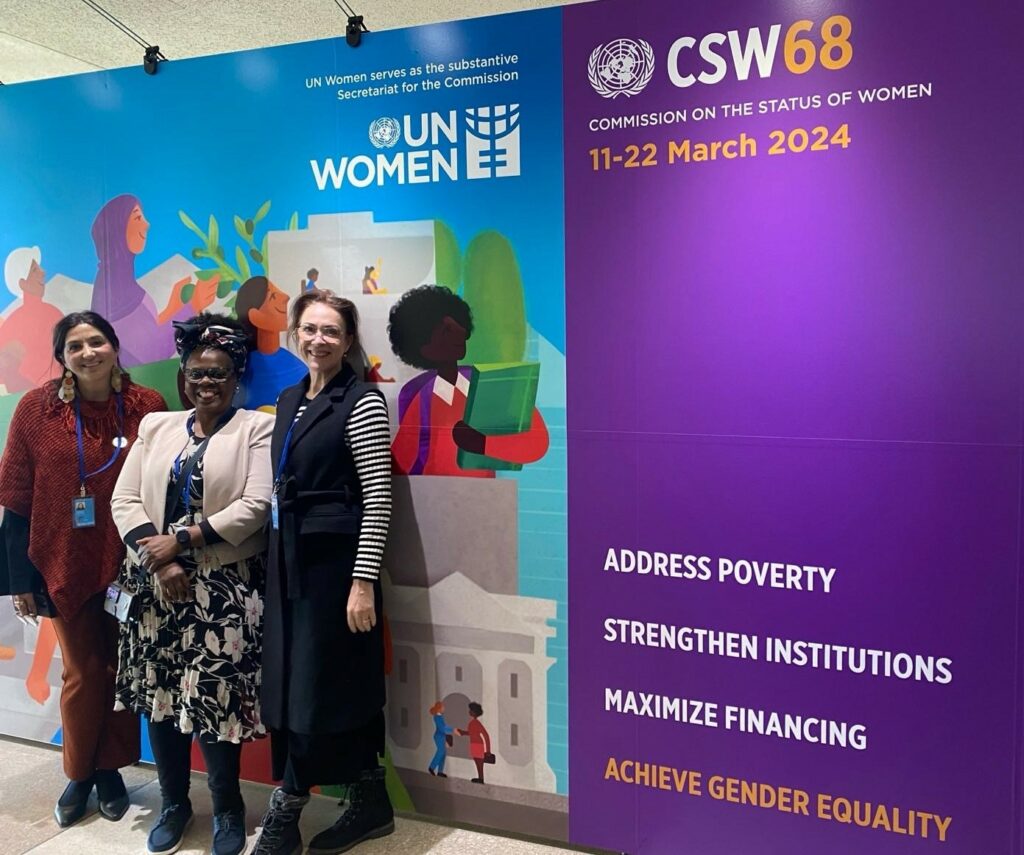 DCA's delegation to the CSW68 stands in front of a UN Women banner