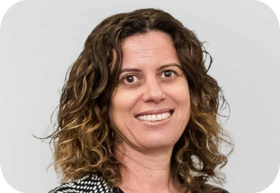 Headshot of Annie Pettit who has short, curly hair and wears a patterned, black top.