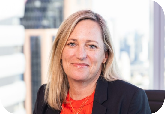 Headshot of Julie Canepa. Julie is a white woman with blonde, shoulder-length hair and blue eyes. She wears an orange blouse and blue blazer.