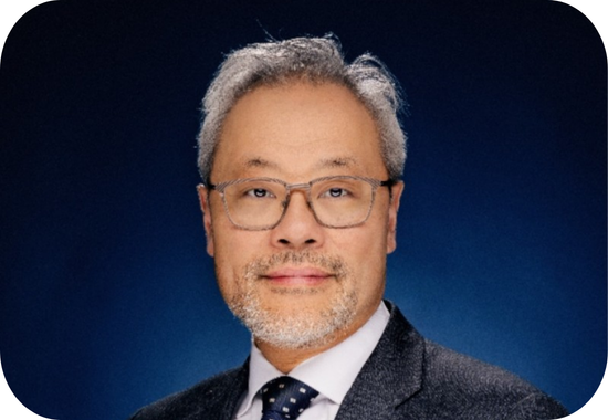 Headshot of Peter Chun, a middle-aged man with grey hair and beard. Chris wears a black and white suit and glasses.