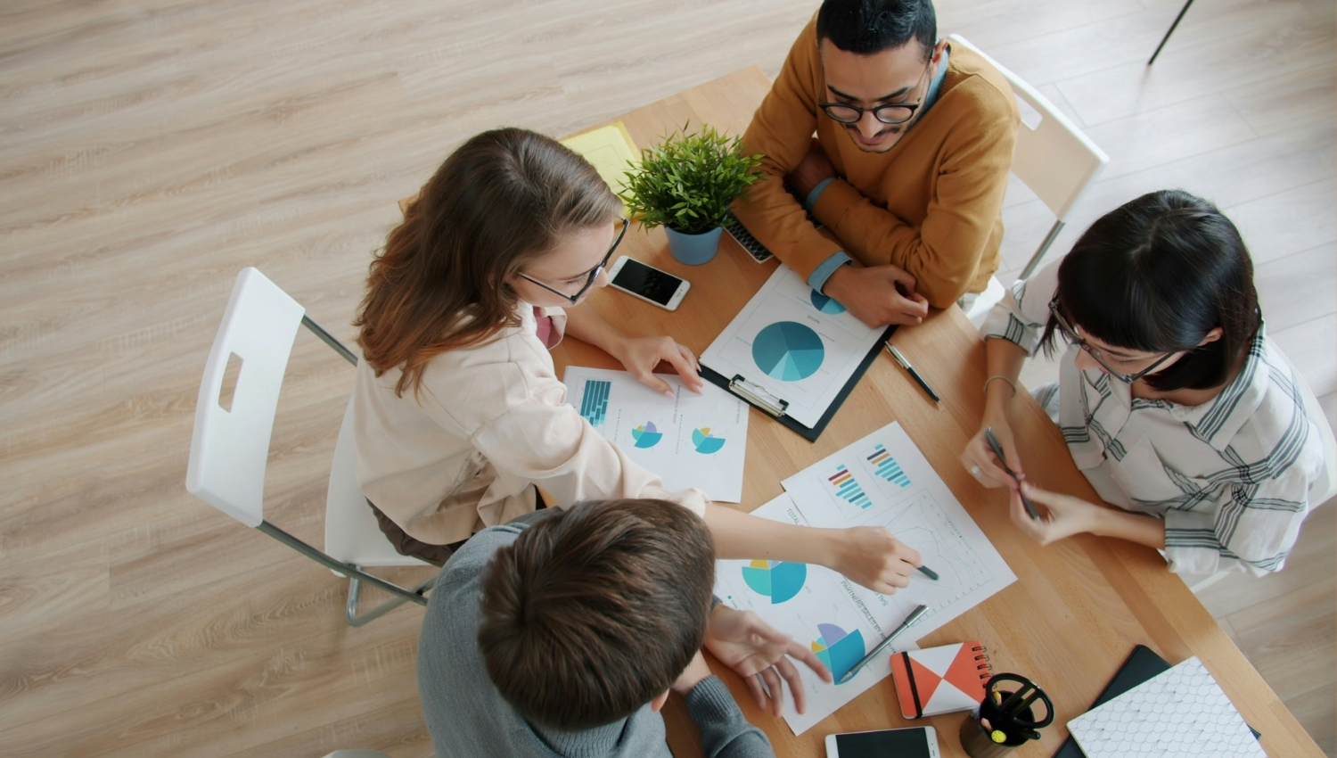 Four people sitting around a table and working on some graphs.