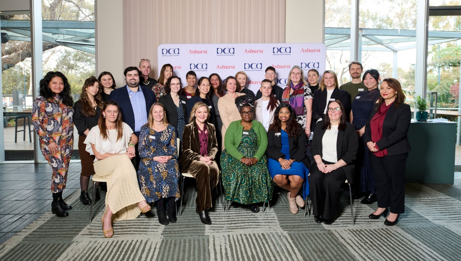 Team photo of Diversity Council Australia staff in formal work wear, smiling at the camera.