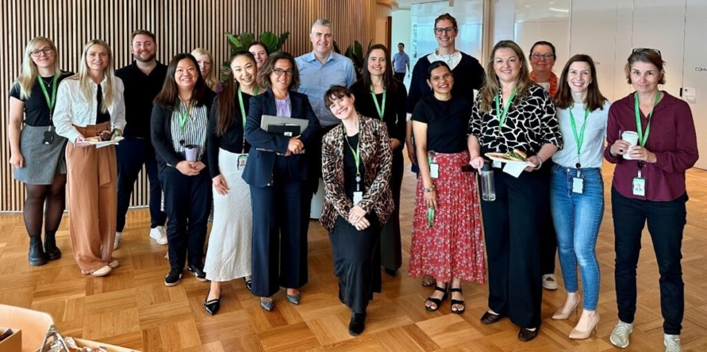 17 employees standing in a group looking directly at the camera and smiling