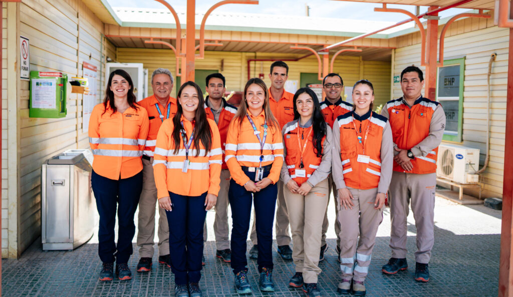 Five women and five men in high-visibility clothing stand in front of a building together, smiling at the camera.