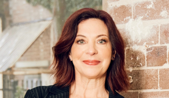 Catherine Fitzpatrick: a woman with shoulder length copper coloured hair and a black pinstriped blazer smiling at the camera.