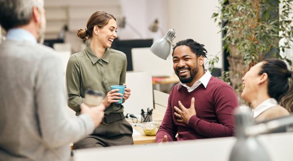 Happy business team having fun while talking on their coffee break in the office. Multi-ethnic group of entrepreneurs laughing while talking to each other on a break in the office.